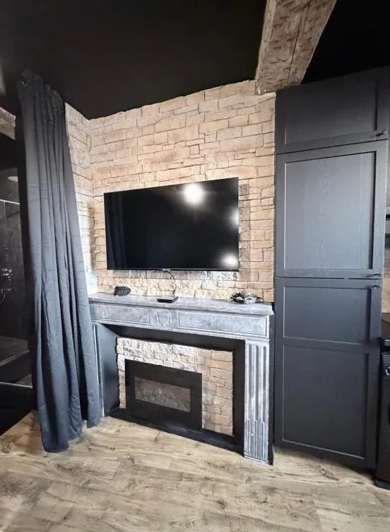 La cheminée décorative et la télévision sur le mur en pierre