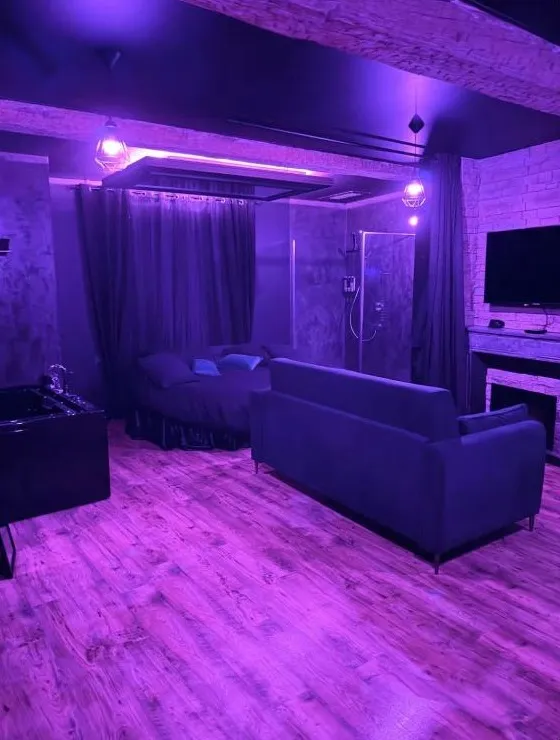 Le séjour et le lit rond en ambiance violette, douche à l'italienne au fond