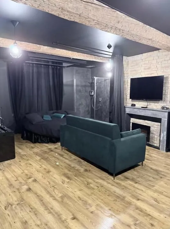 Vue d'ensemble de l'appartement : canapé émeraude, lit rond derrière les rideaux et douche à l'italienne